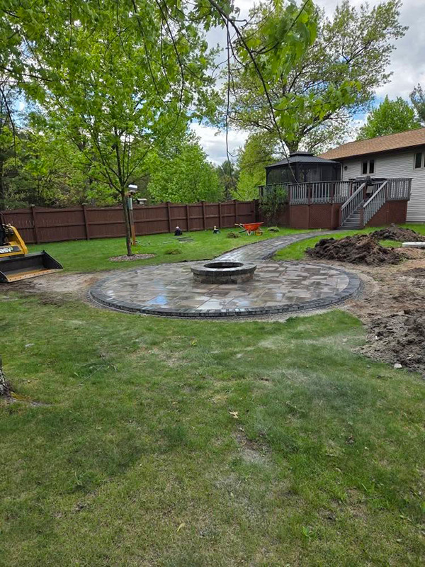 Circular paver patio with a center fire pit under construction in a residential backyard in Nekoosa, Wisconsin