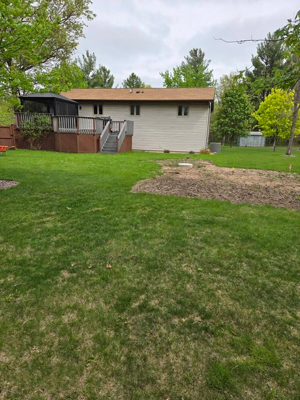 Residential backyard before landscaping with a graded area prepared for patio installation in Nekoosa, Wisconsin