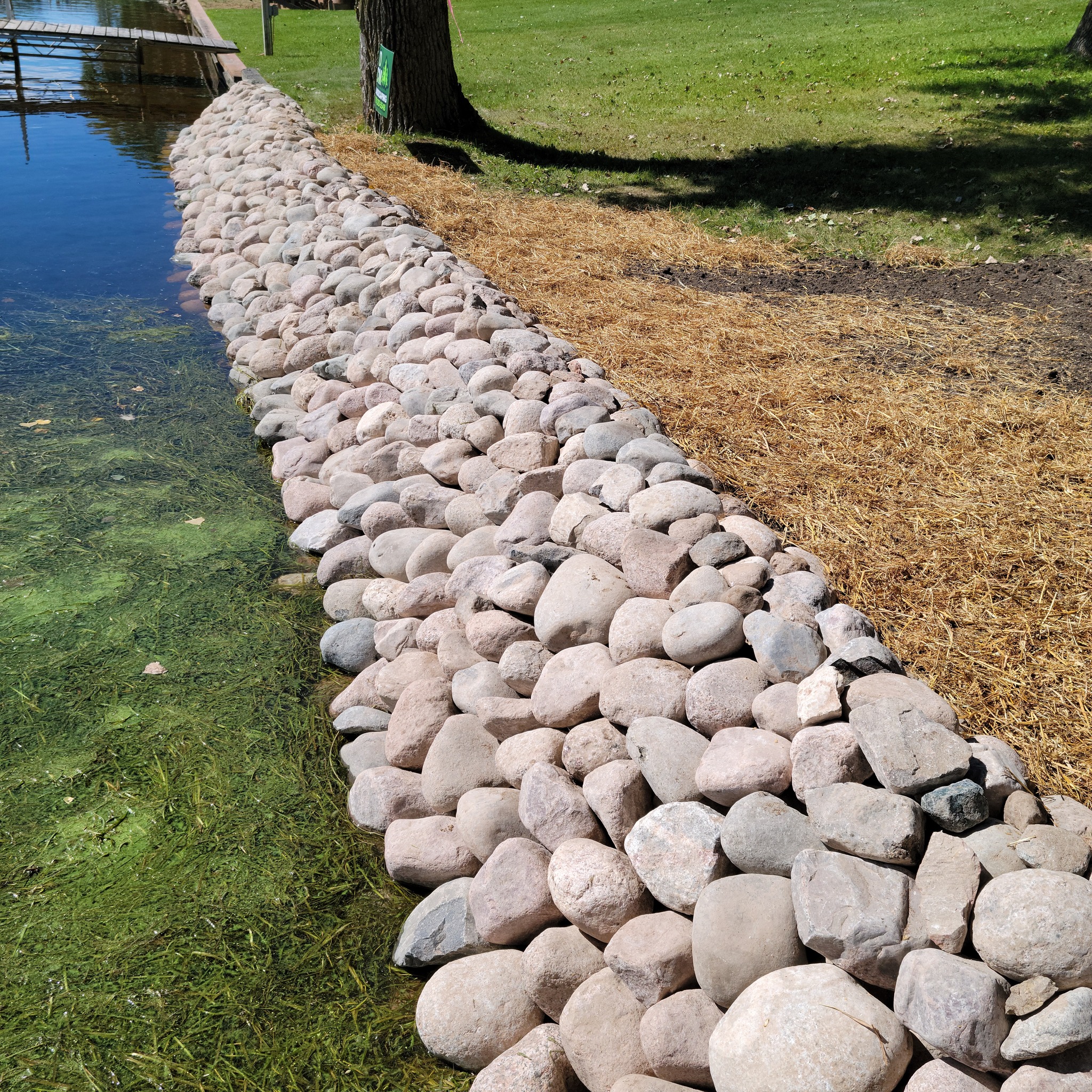 Shoreline erosion control installation with large round boulders along a lakefront property in Nekoosa, Wisconsin